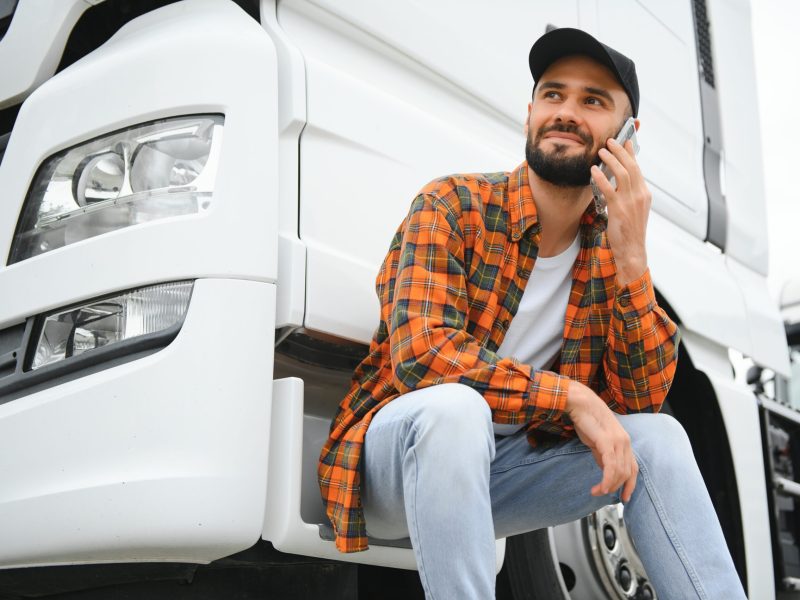 Man trucker talking on the phone by his white truck